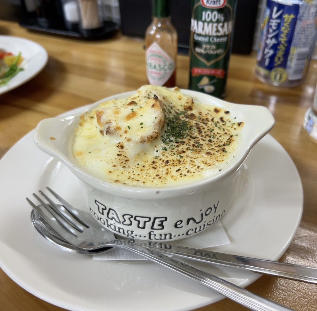 alt="チーズたっぷりで熱々の焼きパンのグラタン。居酒屋ながら本格的な味が楽しめる（ダイニング味味屋・筆者撮影）"
