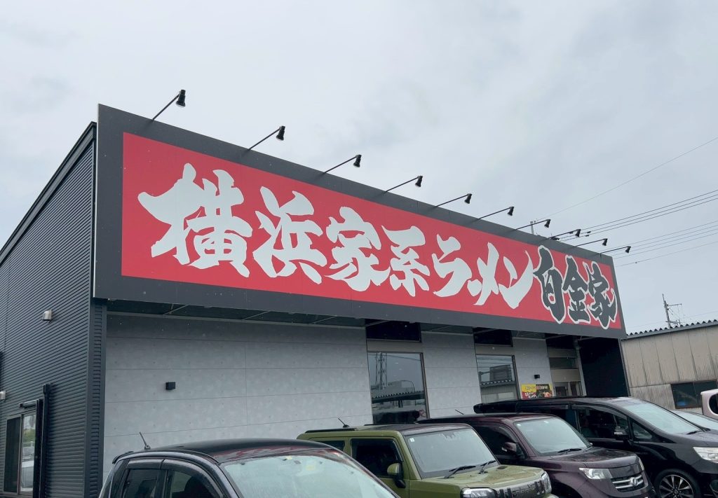 alt="横浜家系ラーメン白金家 浜線バイパス店の店舗外観と大きな看板(筆者撮影)"